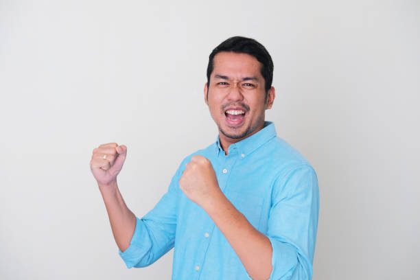 adult asian man showing success gesture with his both hand clenched